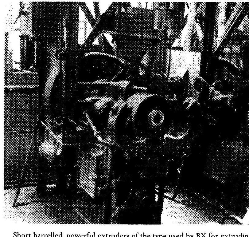 A black and white industrial photograph of short-barrelled extrusion machines in a factory hall.