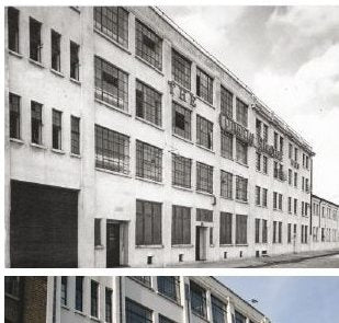 A black and white photograph of a long four-storey brick and rendered industrial building with tall metal-framed windows, its upper wall lettered THE CONWAY STEWART.